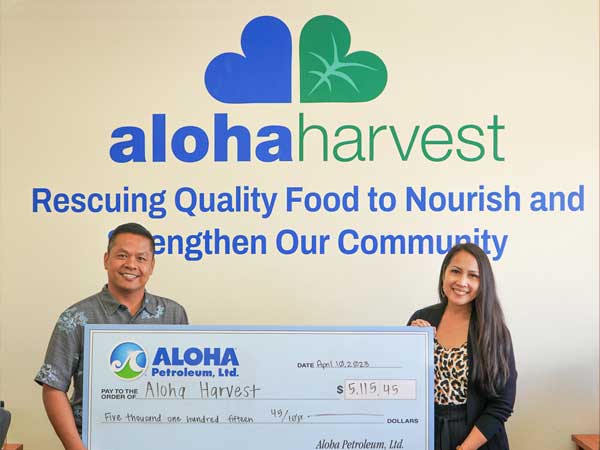 Aloha representative hands check to Aloha Harvest employee.