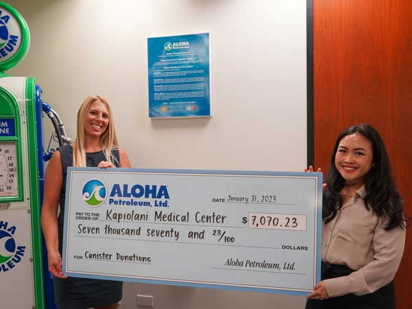 Aloha representative hands check to medical center employee.